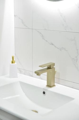 a bathroom sink with a mirror and a gold faucet at Lux Iva apartman in Doboj