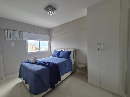 a bedroom with a blue bed and a window at AP Alecrim Porto Real Suítes com Tela de Proteção Praia Privativa in Mangaratiba