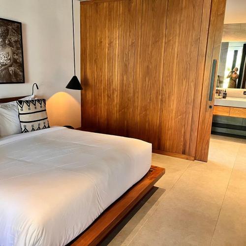 a bedroom with a large bed and a wooden wall at Angel's Villa & Resort in Selong