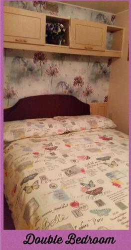 a bed with a bedspread with flowers on it at The Chase & Grange caravan park ingoldmells ref F in Addlethorpe