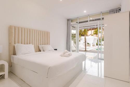 a white bedroom with a large bed and a balcony at 3BR Spa Villa, Outdoor Cinema, Sauna & Ice Bath in Ubud
