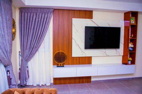 a living room with a tv and purple curtains at Perf Deluxe in Accra