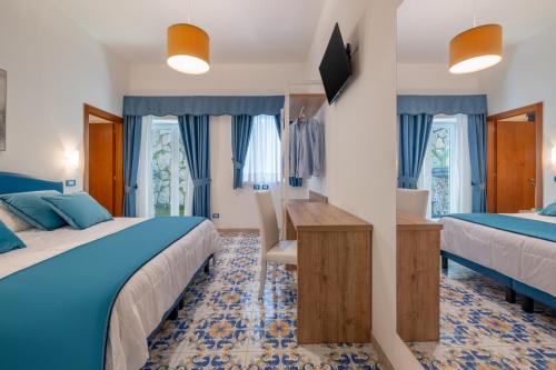 a hotel room with two beds and a desk at Hotel Britannia in Sorrento