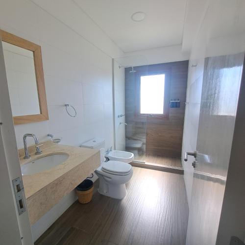 a white bathroom with a toilet and a sink at Apart entre viñas in Cafayate
