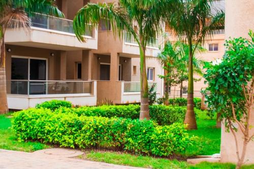 a building with palm trees and bushes in front of it at Perf Deluxe in Accra