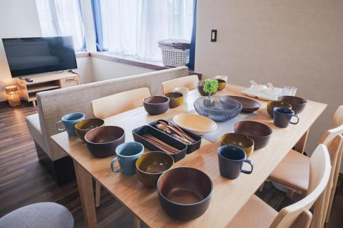 a wooden table with bowls and cups on it at kuki 67ｍ2 Modern Japanese style Toys for kids 2Bedroom in Kuki