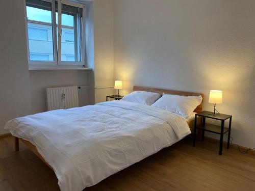 a bedroom with a large white bed with two lamps at Maison Tivoli in Huningue