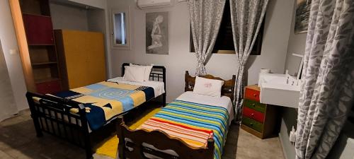 two twin beds in a room with curtains at patra's sea front apartment in Flámbouras