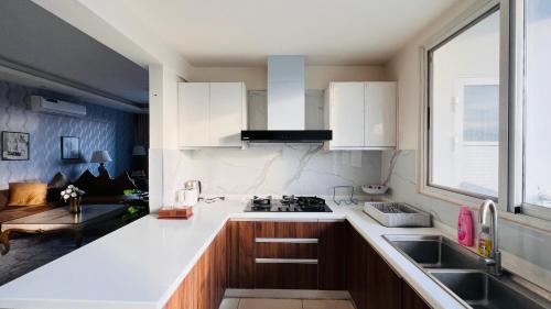 a kitchen with white cabinets and a sink and a window at Skyline Hotel Apartments-Elysium Tower Facing Centaurus Mall Islamabad in Islamabad