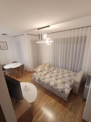 a bedroom with a bed and a table and a desk at Apartman P&N Stara Pazova in Stara Pazova
