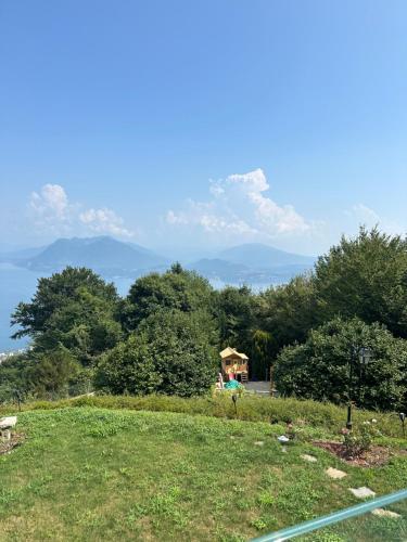 a grassy hill with a gazebo and mountains in the background at Private Luxury Spa & Silence Retreat with Spectacular View over the Lake Maggiore in Stresa