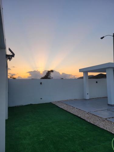 a white wall with a bench and a green lawn at La Vecchia Village Spacious Private Pool Area in Guayama