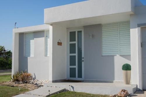 a white house with a blue door and window at La Vecchia Village Spacious Private Pool Area in Guayama