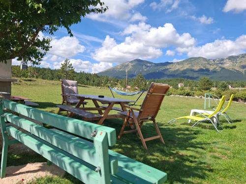 three chairs and a picnic table with mountains in the background at Green cottage in Blidinje