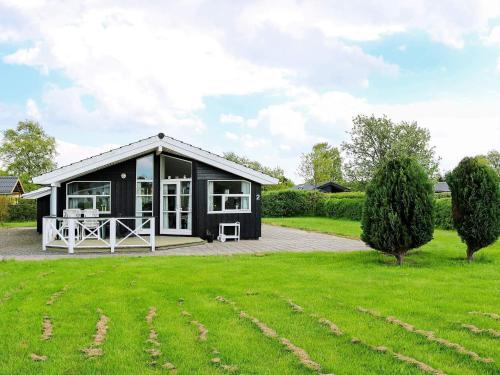 a black cottage with a patio in a yard at 6 person holiday home in Hadsund-By Traum in Øster Hurup