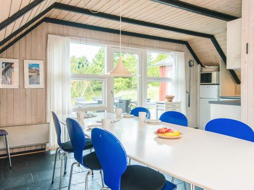 a dining room with a white table and blue chairs at 4 star holiday home in Rømø in Kongsmark