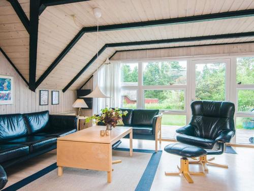 a living room with black leather furniture and windows at 4 star holiday home in Rømø in Kongsmark
