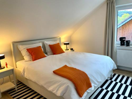 Un dormitorio con una cama con almohadas naranjas y una ventana. en Urlaub in der Eifel am Rursee - Wita31, en Einruhr