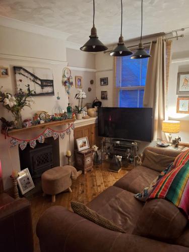 a living room with a couch and a television at Double Ensuite in a colourful quirky terrace on a quiet leafy street in Enderby