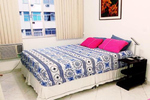 um quarto com uma cama com duas almofadas cor-de-rosa em Coração Copacabana Figueiredo 219 no Rio de Janeiro