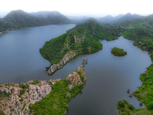 an aerial view of a large lake between mountains at Footprint By The Lake in Udaipur