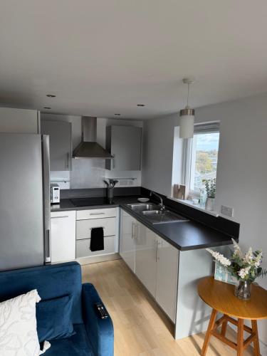 a kitchen with white cabinets and a blue couch at Basingstoke Train Station Short Stay in Basingstoke