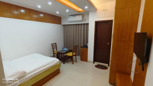 a bedroom with a bed and a table and a television at The Castle Inn in Dhaka