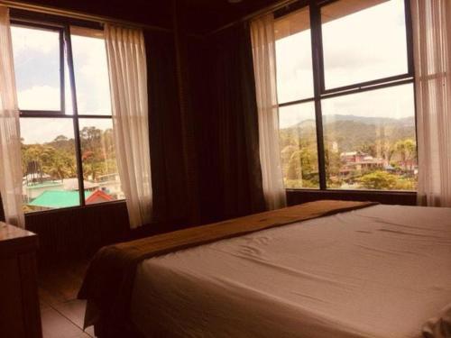 a bedroom with a bed and windows with a view at Dolphin Residency in Thekkady