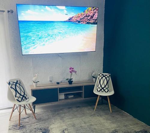 a room with two chairs and a tv on a wall at Discover Paradise in Discovery Bay