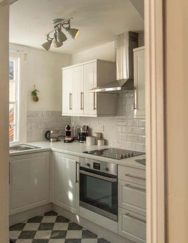 a kitchen with white cabinets and a stove top oven at Milliners Court - One-Bed Cottage in Central Bath in Bath