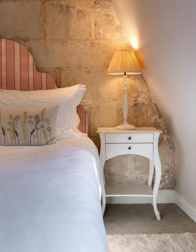 a bedroom with a bed and a lamp on a nightstand at Milliners Court - One-Bed Cottage in Central Bath in Bath