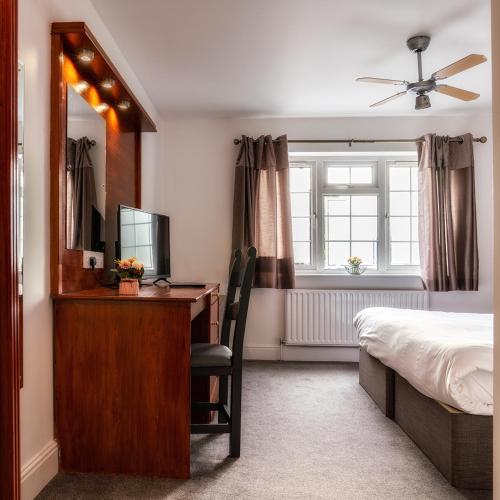 a bedroom with a desk with a bed and a mirror at Club Wokingham Hotel in Wokingham