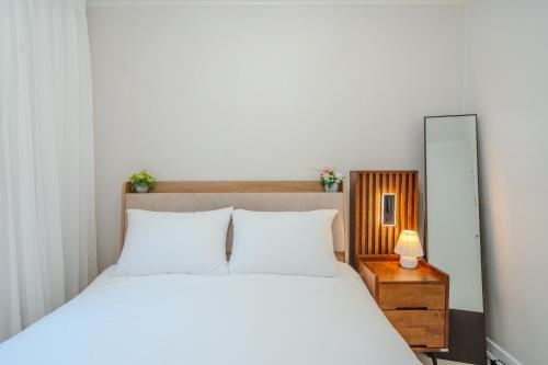 a bedroom with a large white bed and a mirror at Cozy Haven in Suwŏn-yŏk