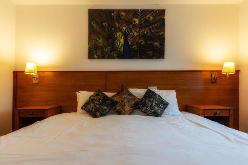 a white bed with pillows and a painting on the wall at Club Wokingham Hotel in Wokingham