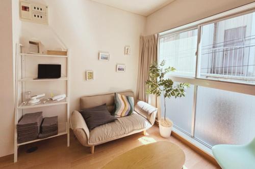 a living room with a couch and a large window at Apartment Hotel 高松裏路地 201 高松 古馬場町 in Takamatsu