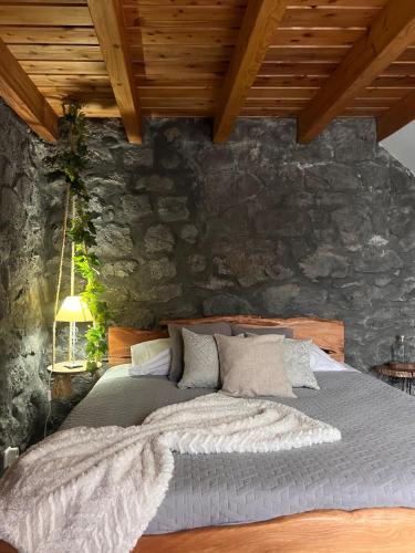 a bed in a room with a stone wall at Vigia dos Machados in Lajes do Pico