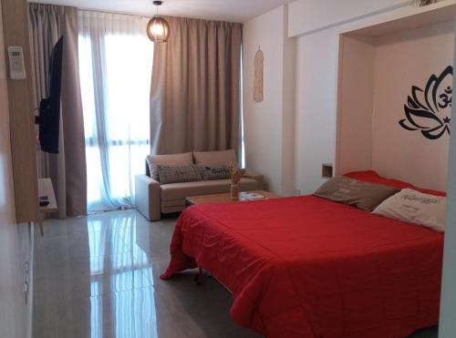 a bedroom with a red bed and a couch at Torres Brickell Departamento -MALVAN- 1A in Tigre