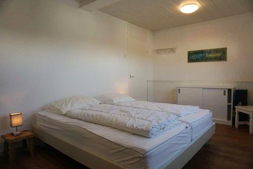 a large white bed in a room with a lamp at Keizerskroon 237 in Julianadorp