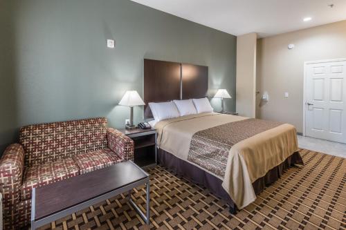 um quarto de hotel com uma cama e um sofá em Scottish Inns & Suites em Balch Springs