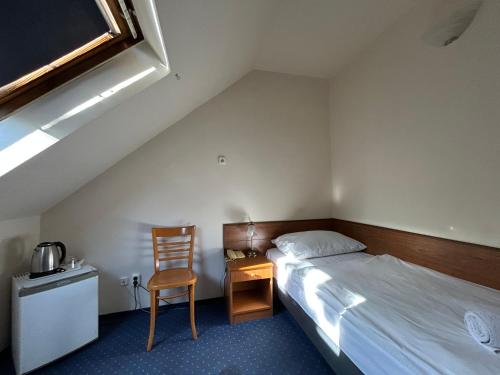 a small bedroom with a bed and a chair at Corvin Hotel in Győr