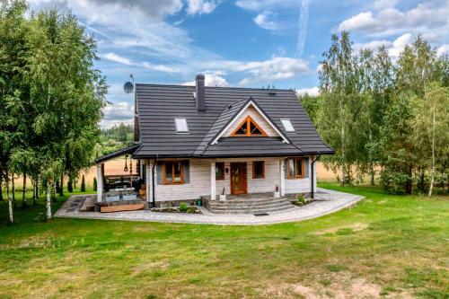 a house with a black roof on a green yard at Rodzinne wczasy nad Czarną Hańczą 