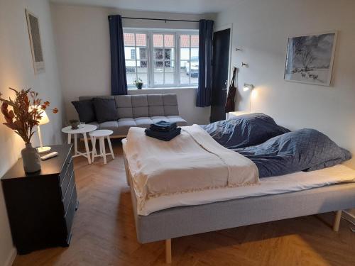 a bedroom with a bed and a couch in it at Mini-lejlighed med køkken - deler bad og toilet med nabolejlighed 2 in Asperup