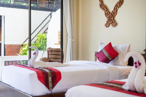 two beds in a room with swans on them at JR Siam Inn Resort in Kata Beach
