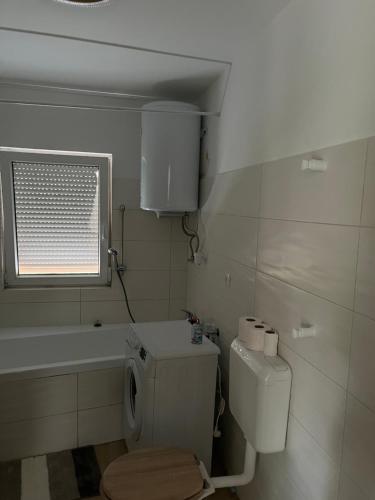 a white bathroom with a toilet and a window at Zöldkert Kecskemét in Kecskemét