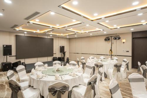 a conference room with tables and chairs and a screen at Iconique Hotel Nha Trang in Nha Trang