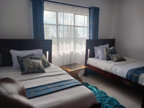 two beds in a room with a window at Sere Cozy Home in Wundanyi