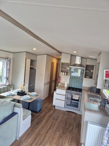 a kitchen and living room with a couch and a table at Meadow Banks Combe Haven in Hastings