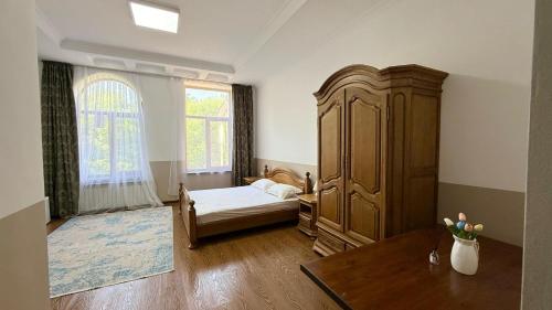 a bedroom with a bed and a large wooden cabinet at Promenade Park Hotel in Shymkent