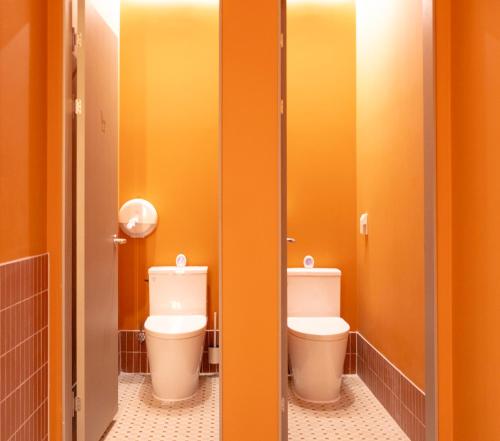 two toilets in a bathroom with orange walls at THE EXTAY Lounge Jongno in Seoul