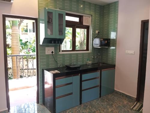 a kitchen with green walls and a sink and a window at Plams Beach comfort in Benaulim